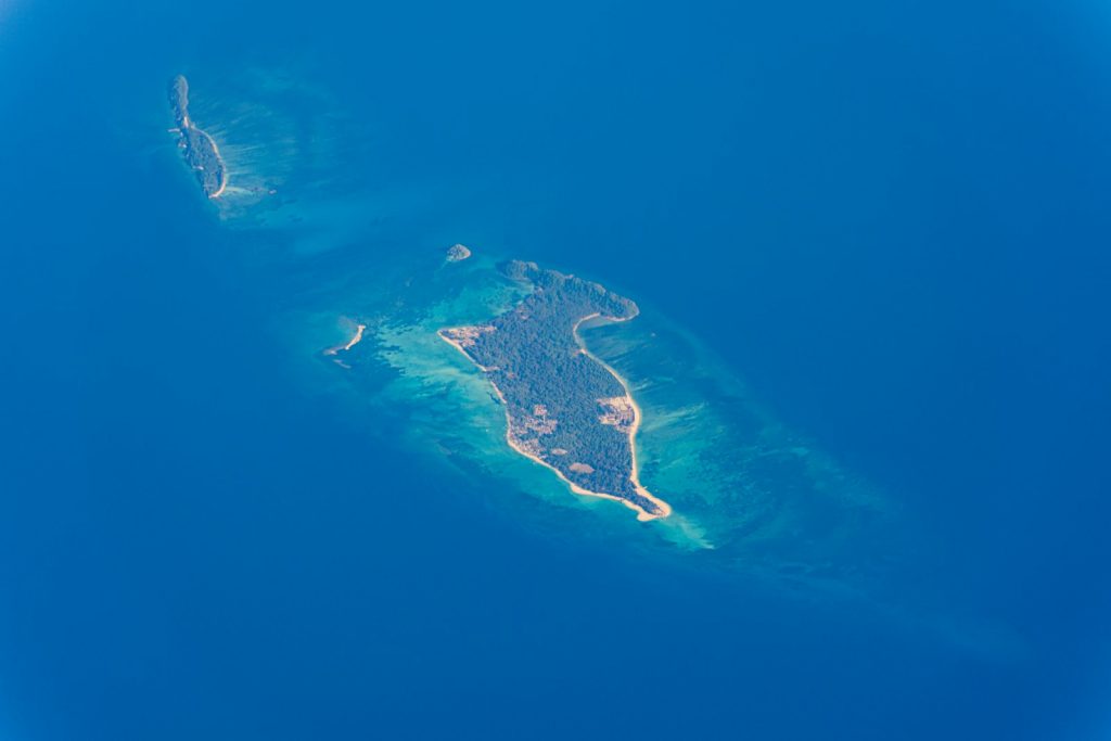 Aerial view of a tropical island surrounded by blue ocean.